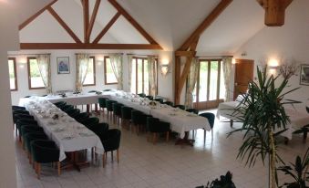 a large , empty dining room with multiple tables and chairs , set for a formal dinner at Logis Hotel Restaurant de l'Abbaye