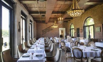 a large dining room with multiple tables and chairs arranged for a group of people to enjoy a meal at Oheka Castle Hotel & Estate