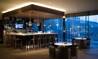 a modern bar area with a long wooden bar and several chairs surrounding it , creating a cozy atmosphere at AC Hotel Cincinnati at Liberty Center