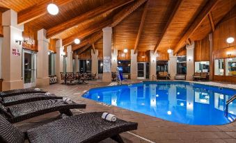 an indoor swimming pool surrounded by lounge chairs and umbrellas , providing a relaxing atmosphere for guests at Garden Court Hotel Aylesbury