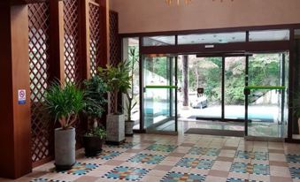 a hotel lobby with a mosaic tile floor , multiple potted plants , and a glass door leading to the outside at Hotel Chalet