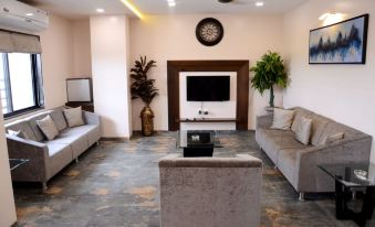 a modern living room with a gray couch , white walls , and a tv on the wall at Hotel Paradise