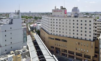 a busy city street with several cars , trucks , and buses driving down the road , as well as pedestrians walking on the sidewalk at Kichijoji Tokyu Rei Hotel