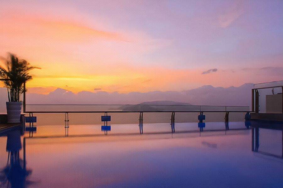 a serene sunset over a mountainous landscape , with a swimming pool and chairs on the deck at DTX Hotel Nha Trang