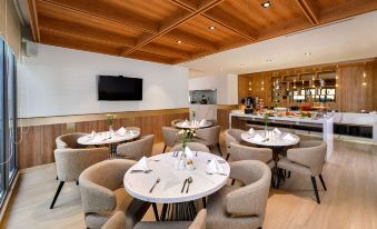 a dining room with a wooden ceiling , multiple round tables and chairs , and a tv on the wall at Oakwood Apartments Pik Jakarta