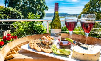 a wooden dining table with a plate of food , wine , and a view of the water at Tamar House