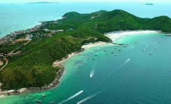 An aerial view shows boats in the water, an island on land near the beach in the distance at Mera Mare Pattaya