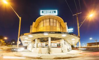 "a modern , curved building with a blue sign reading "" motel "" and an arched entrance , set against the backdrop of a city street at" at Airport Hotel Sydney