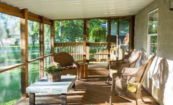 a wooden porch with wicker furniture , a coffee table , and potted plants , overlooking a lake at Amish Country Comfort