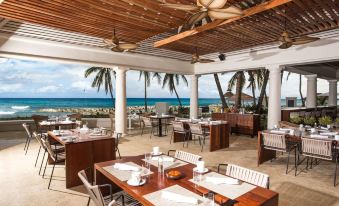 The top floor of an exotic resort features a beachfront restaurant with tables and chairs at The Ritz-Carlton Golf & Spa Resort, Rose Hall, Jamaica