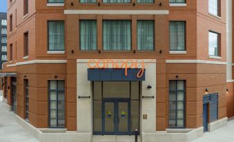 "a brick building with an orange sign that says "" canspa "" and "" travel "" on it , as well as windows" at Canopy by Hilton Ithaca Downtown