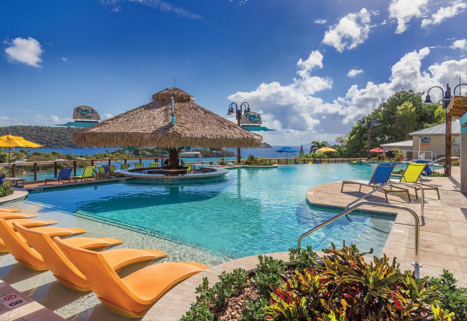 a large swimming pool with lounge chairs and a thatched umbrella , surrounded by lush greenery at Margaritaville Vacation Club by Wyndham - St Thomas