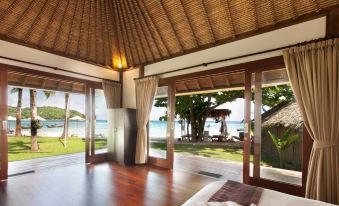 a large bedroom with a bed , hardwood floors , and a view of the ocean through large windows at Mali Resort Pattaya Beach Koh Lipe