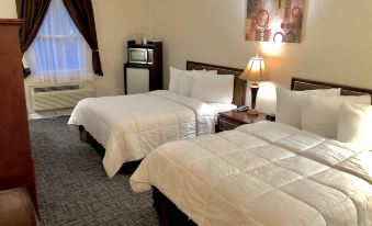 a hotel room with two beds , a desk , and a window , all neatly arranged on a carpeted floor at Bicentennial Inn