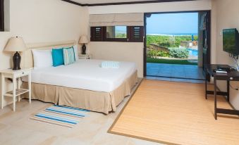 a bedroom with a large bed , white linens , and a view of a lake through a sliding glass door at Santosha Barbados