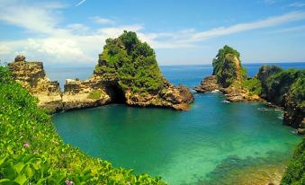 a picturesque view of a rocky coastline with a clear blue ocean and a small island in the distance at Tunak Cottage