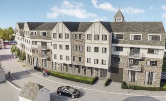 a large apartment building with multiple floors and balconies , surrounded by trees and parked cars at Mercure HAN Sur Lesse