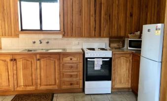 a kitchen with wooden cabinets , a white stove , and a microwave oven on the counter at Great Lake Hotel
