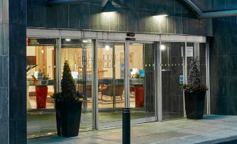 a city street at night , with a hotel entrance and several potted plants lining the sidewalk at Leonardo Hotel Middlesbrough