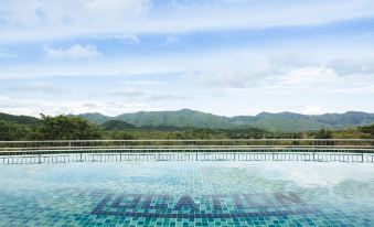 a large swimming pool surrounded by a patio , with a view of mountains in the background at The Location