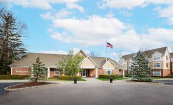 a large building with a flagpole and the american flag flying in front of it at Residence Inn Saddle River