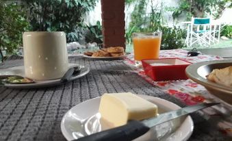 a dining table set with a plate of butter , a cup of coffee , and a glass of orange juice at Casa del Arbol Hostel