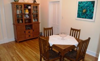 a dining room with a wooden dining table , four chairs , and a bookshelf filled with books at Dolan House B&B