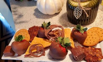 a plate of chocolate - covered strawberries and crackers on a dining table , accompanied by a candle at PineCrest Inn