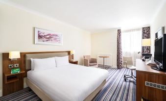 a modern hotel room with a large bed , white sheets , and a striped carpet , along with a desk and chair at Holiday Inn Leeds - Wakefield M1, Jct.40