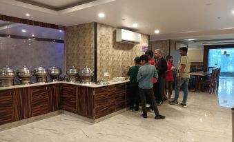 a group of people are standing in a room with marble floors and counter , looking at a buffet line at Royal Garden Resort