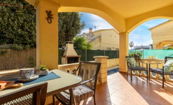 a cozy outdoor dining area with a table , chairs , and a fire pit , surrounded by yellow walls and a brick patio at Sally