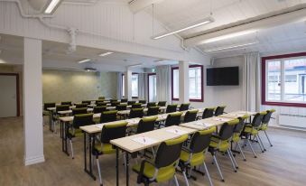 a large conference room with multiple rows of chairs arranged in a semicircle , and a television mounted on the wall at Thon Hotel Hallingdal