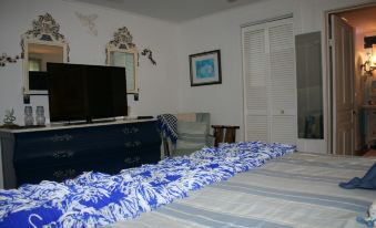 a bedroom with a blue and white bedspread , a television , and a dresser , all decorated in a nautical theme at Lamplight Inn