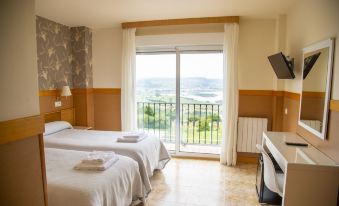 a hotel room with two beds , a balcony offering a view of the ocean , and a flat - screen tv at Hotel Ría de Suances