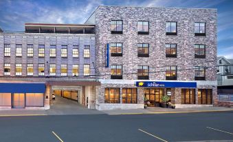 a hotel with a stone facade and blue signage is shown in an urban setting at Scholar Morgantown, Tapestry Collection by Hilton