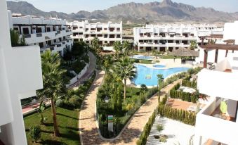 a large apartment complex with a swimming pool surrounded by palm trees , and mountains in the background at Casa Blanca