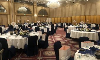 a large banquet hall with numerous round tables and chairs set up for a formal event at Imabari Kokusai Hotel
