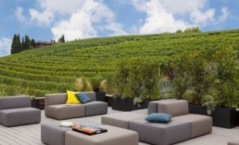 a rooftop patio with multiple couches , chairs , and a dining table , surrounded by lush greenery and a beautiful view of the sky at Arborina Relais