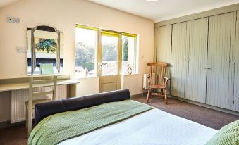 a spacious bedroom with a large bed , a closet , and a door leading to a balcony at Lakeside Cottage