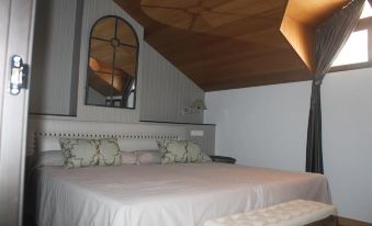 a bedroom with a white bed and a wooden bench , featuring a mirror on the wall at Hotel Villa Maria