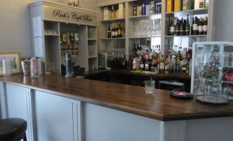 "a bar with a long wooden counter , several bottles of alcohol on shelves behind it , and a sign above the counter reading "" ruh 's" at Balcary House Hotel