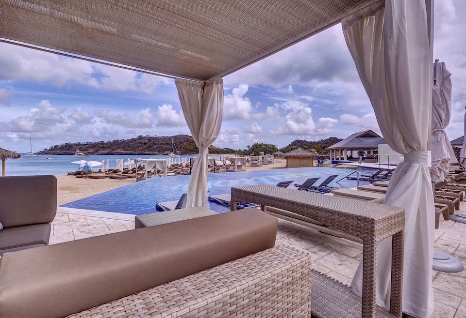 a luxurious outdoor living area with a pool , sun loungers , and a comfortable seating area under a canopy at Royalton Antigua, An Autograph Collection All-Inclusive Resort