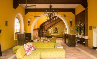 a living room with yellow couches and a chandelier hanging from the ceiling , creating a warm and inviting atmosphere at Hotel Union