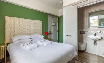 a large bed with white linens and towels is in a room with green walls at Victoria Hotel