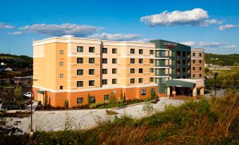 a large , modern hotel building with multiple stories and a parking lot in front of it at Courtyard Pittsburgh Washington/Meadow Lands