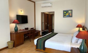 a hotel room with a bed , desk , and tv , along with wooden furniture and a painting on the wall at DAM San Hotel