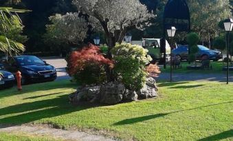 a park with green grass , trees , and a parking lot filled with cars , surrounded by trees and buildings at Ca' Del Bosco