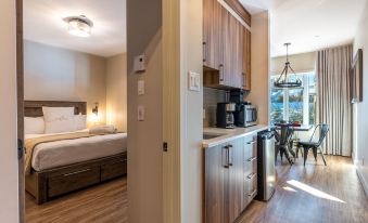 a modern bedroom with a bed and a kitchen area with cabinets and appliances , next to an open doorway leading to another room at Le Viking Resort & Marina