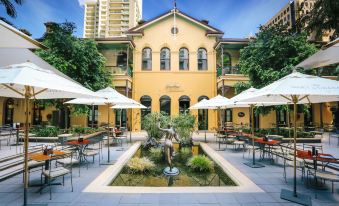 an outdoor dining area with a fountain in the center , surrounded by tables and chairs at Stamford Plaza Brisbane