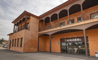 a building with an orange exterior and white trim , featuring balconies on the second floor at Fuente del Miro